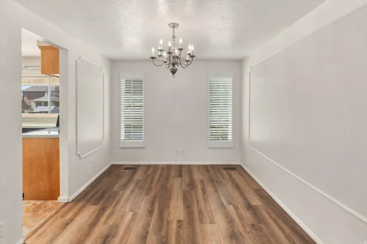 Wood-finish flooring throughout, with decorative wall molding and a central chandelier