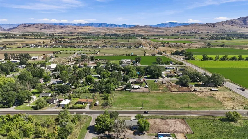 Expansive rural setting with agricultural fields, distant mountains, and established trees
