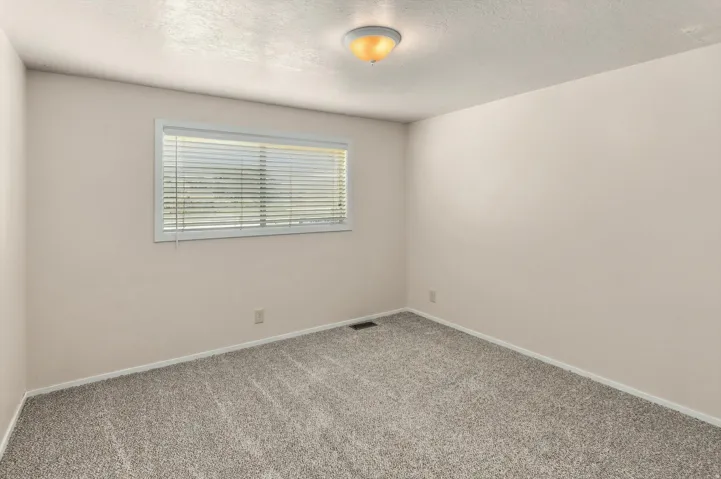 Recessed window with white blinds, neutral wall finishes, and gray textured carpet