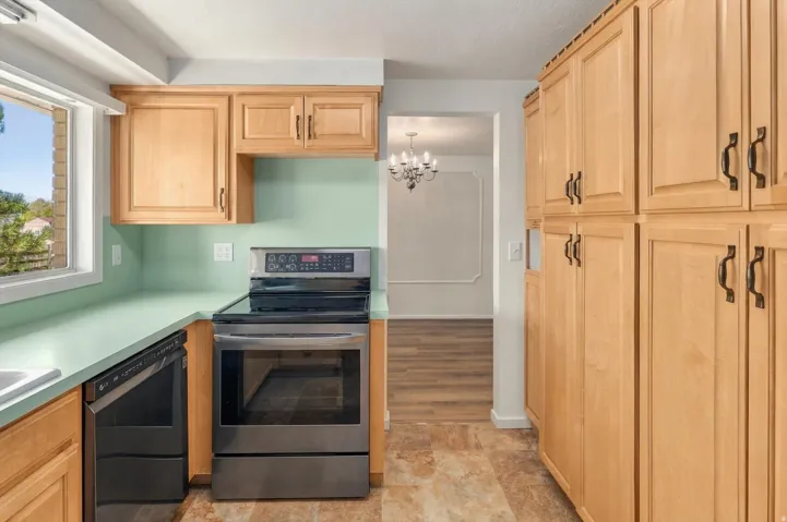 Kitchen featuring light wood cabinetry, light green countertops, and stainless steel appliances