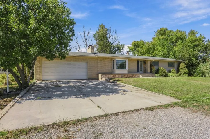 Brick exterior with a prominent front lawn, a concrete driveway, and an attached garage