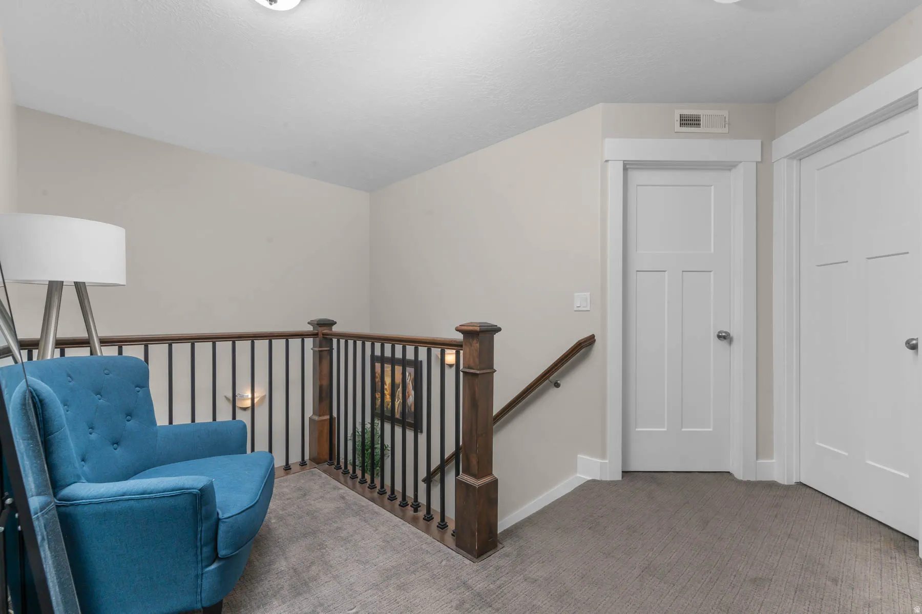 Hardwood newel posts, wrought iron balusters, wood handrail, paneled interior doors, and neutral carpeting
