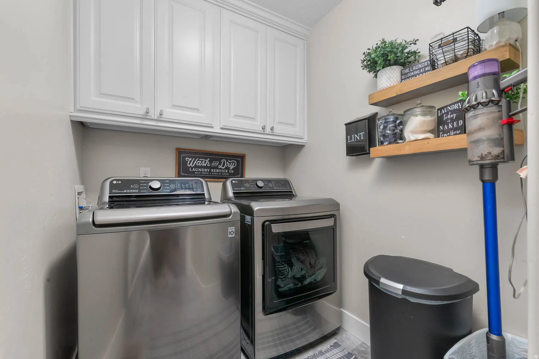 White upper cabinetry, light wall color, and wood-finish floating shelves