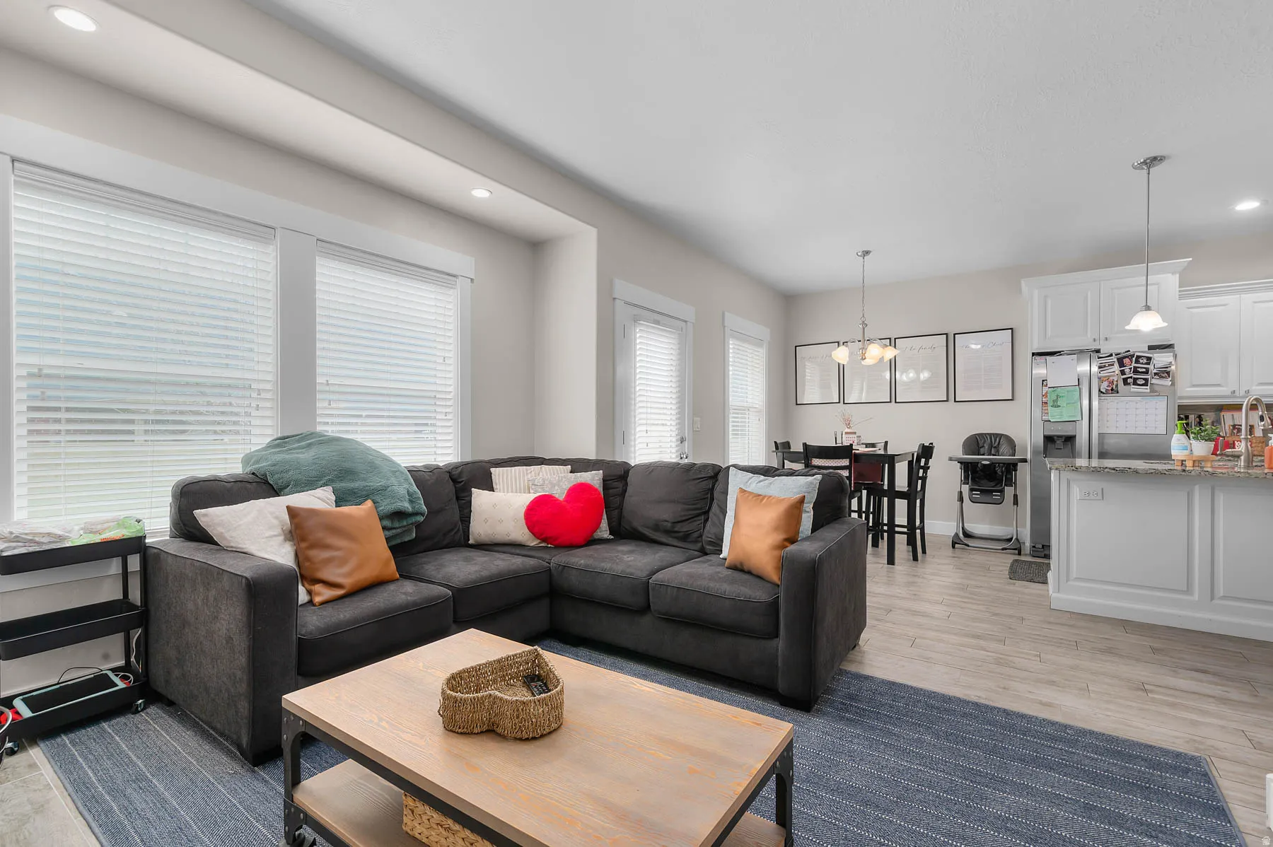 Open-concept living area with wood-finish flooring, recessed lighting, and ample natural light from multiple windows