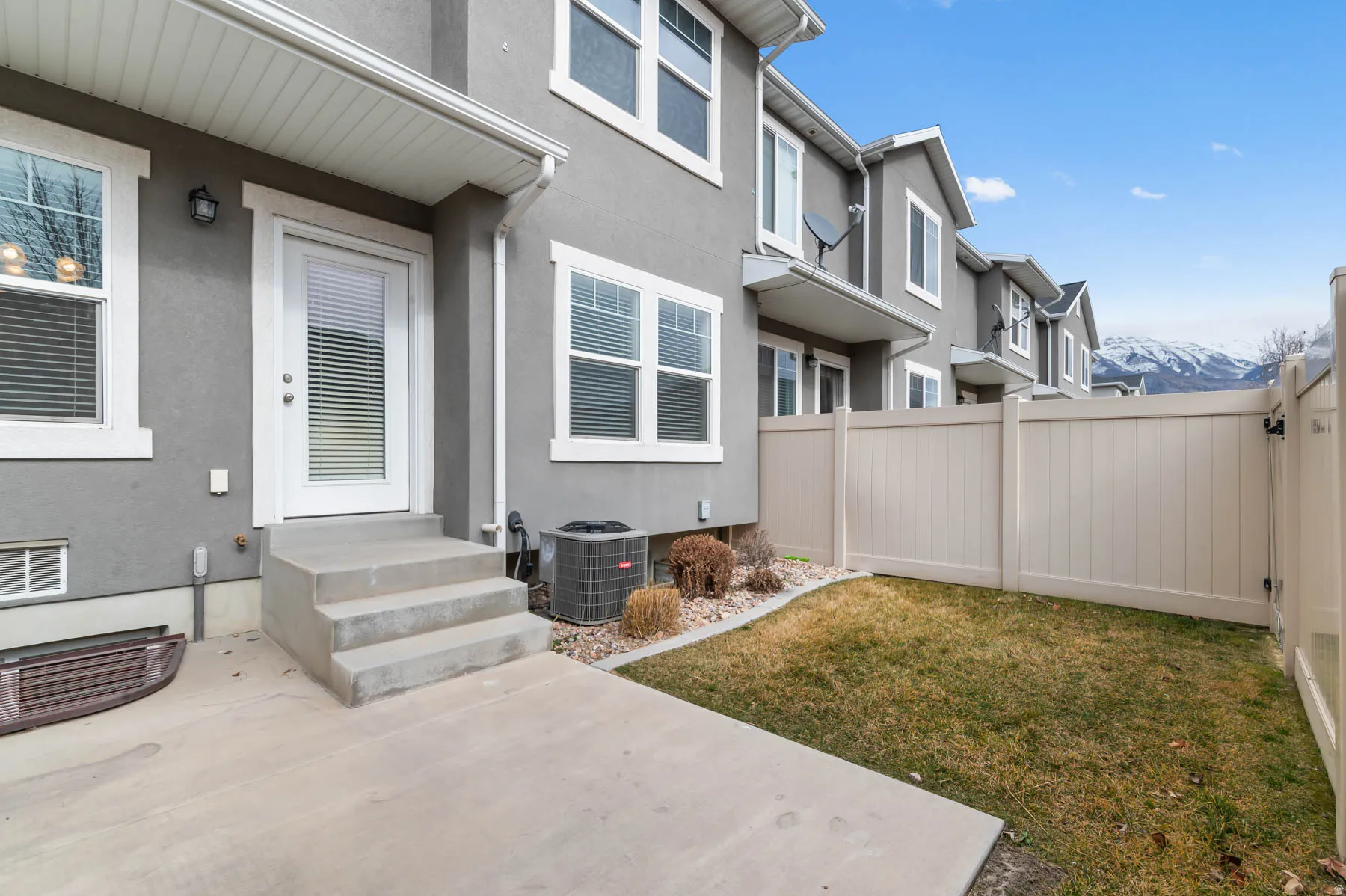 Private patio with concrete steps, leading to a fenced yard with a manicured lawn