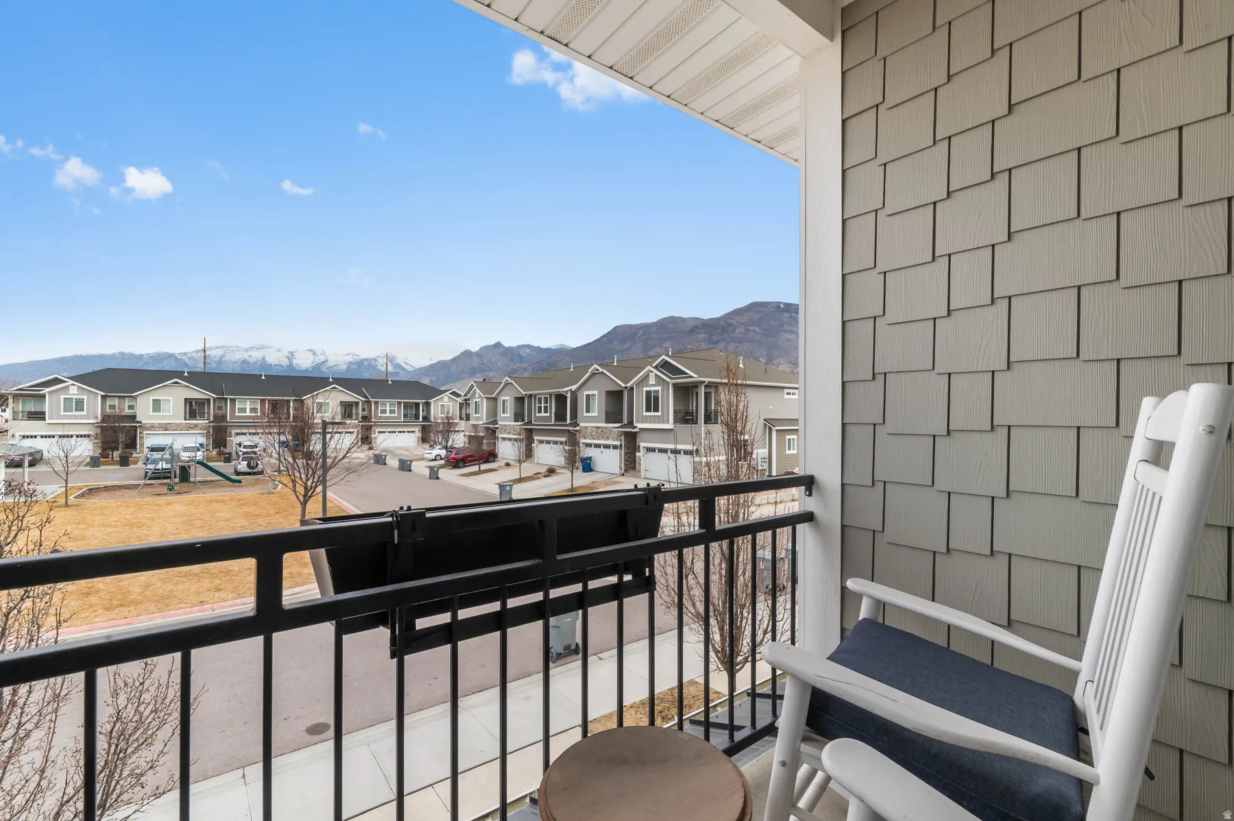 Exterior balcony with black metal railing, gray shaker shingle siding, and mountain scenery