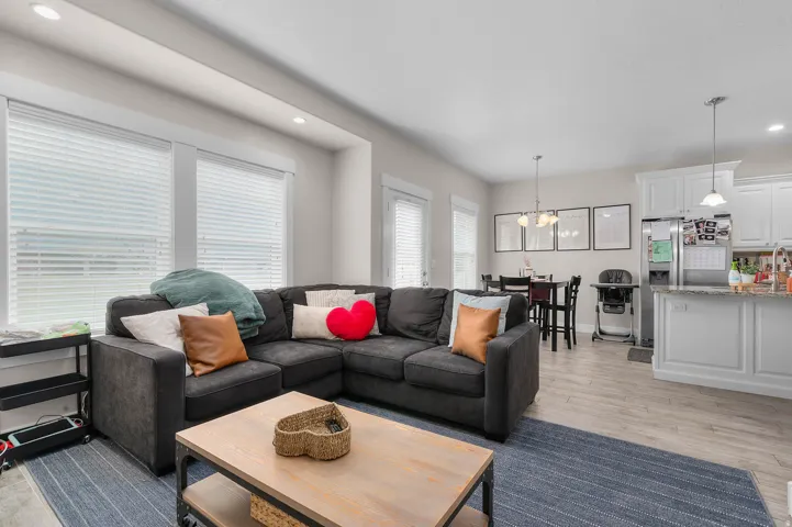 Open-concept living area with wood-finish flooring, recessed lighting, and ample natural light from multiple windows