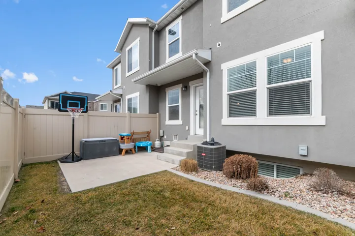 Private fenced backyard with a concrete patio, a grass area, and a rock border