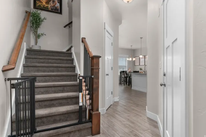 Wood-finish flooring, recessed lighting, white interior doors, and carpeted stairs with a wood railing