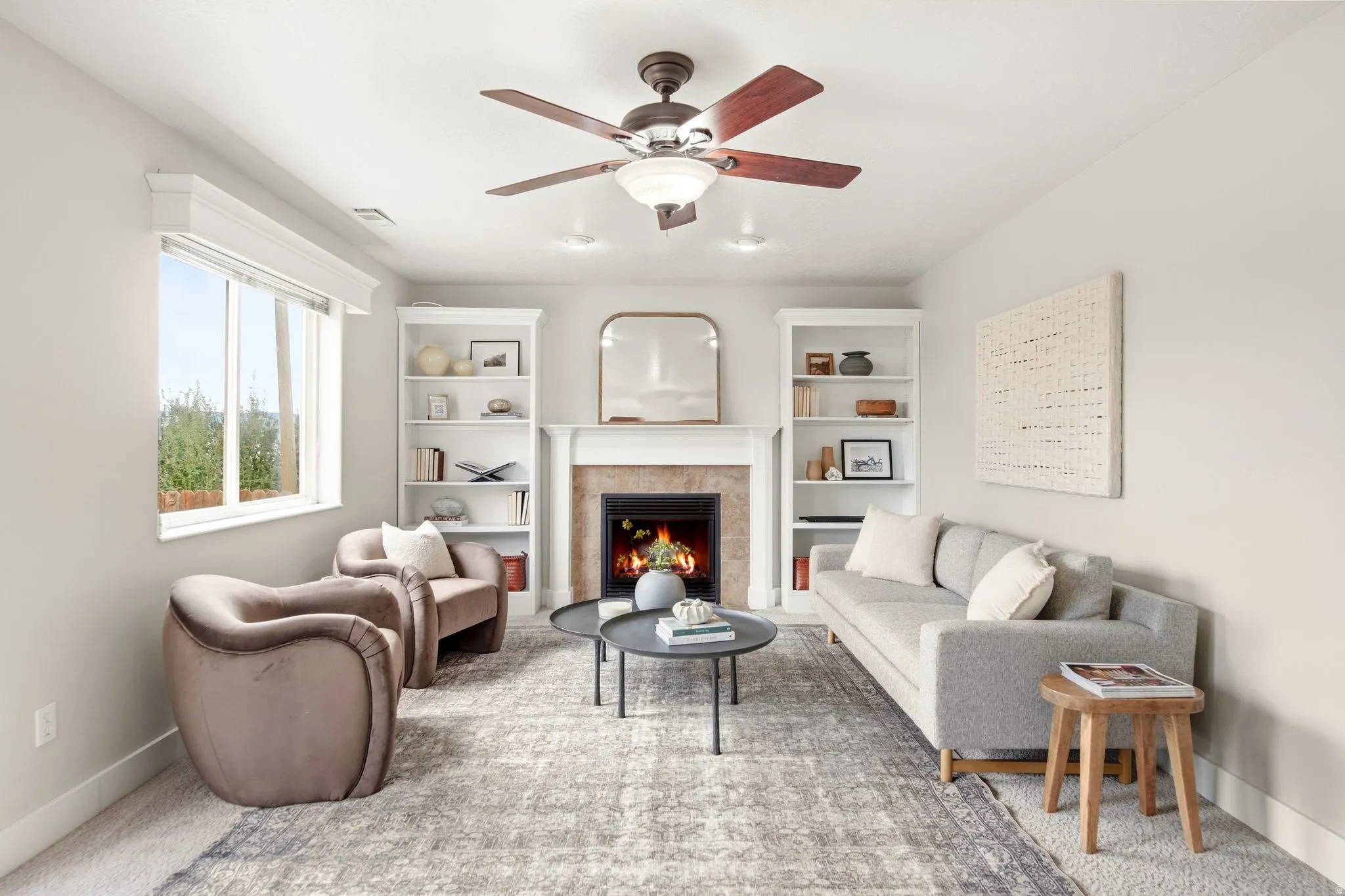 Lower living room off of the garage entrance with a gas fireplace, ample natural light, access to the back deck, and built-in shelving