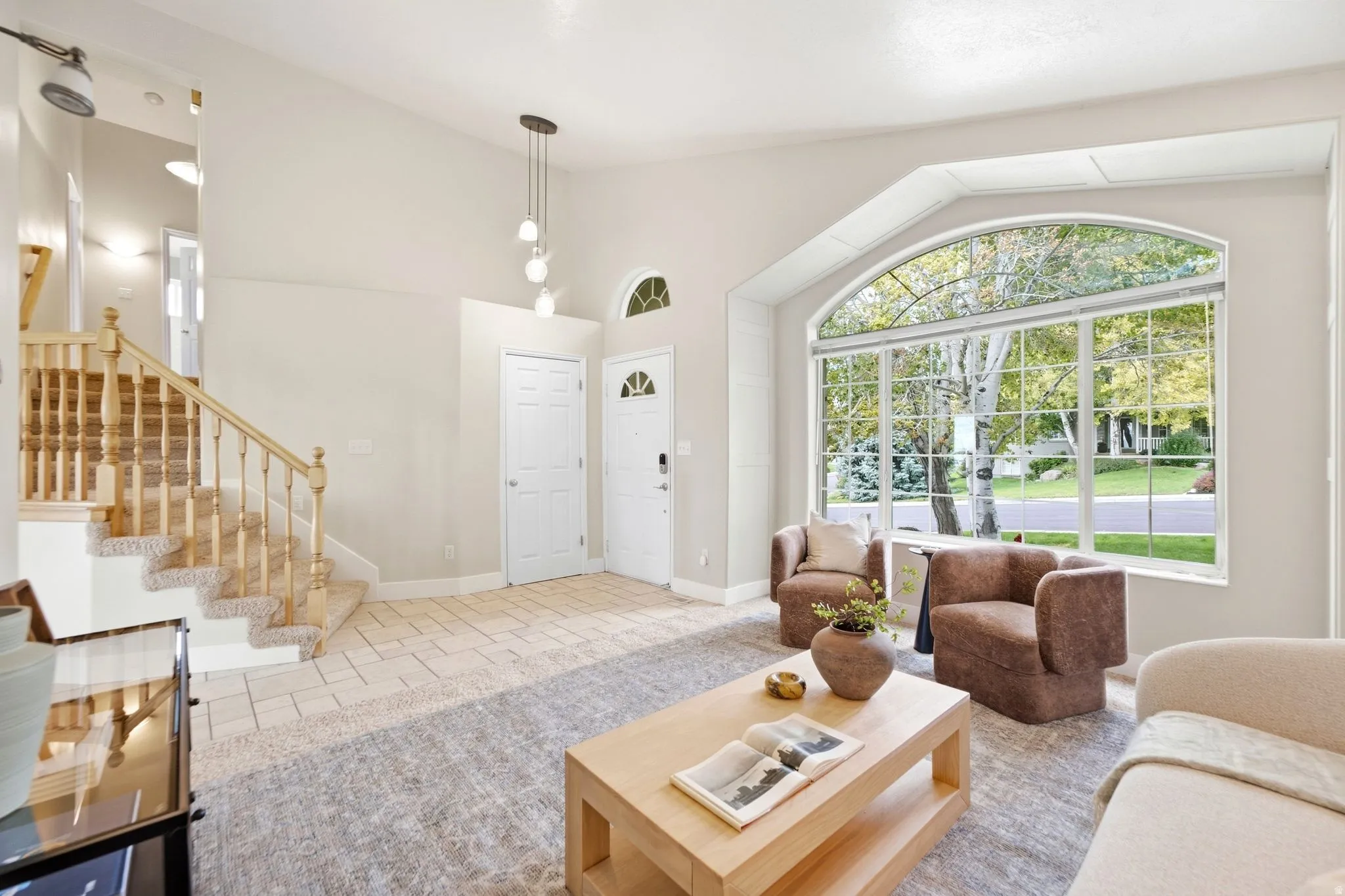 Front living room with a view out the window and looking at the front door, coat closet, and stairs to the upper level