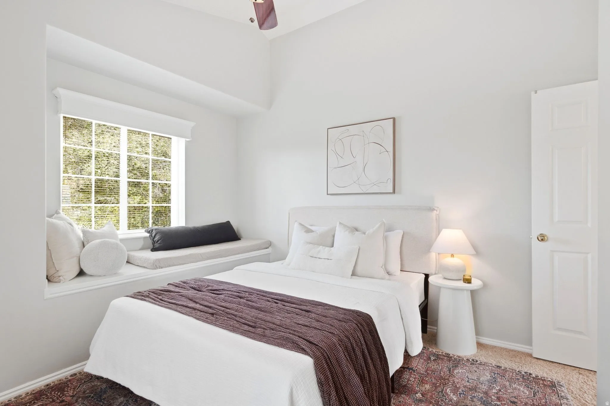 Second upstairs bedroom, across the hall from the primary bedroom, with vaulted ceilings and a cozy reading nook window seat