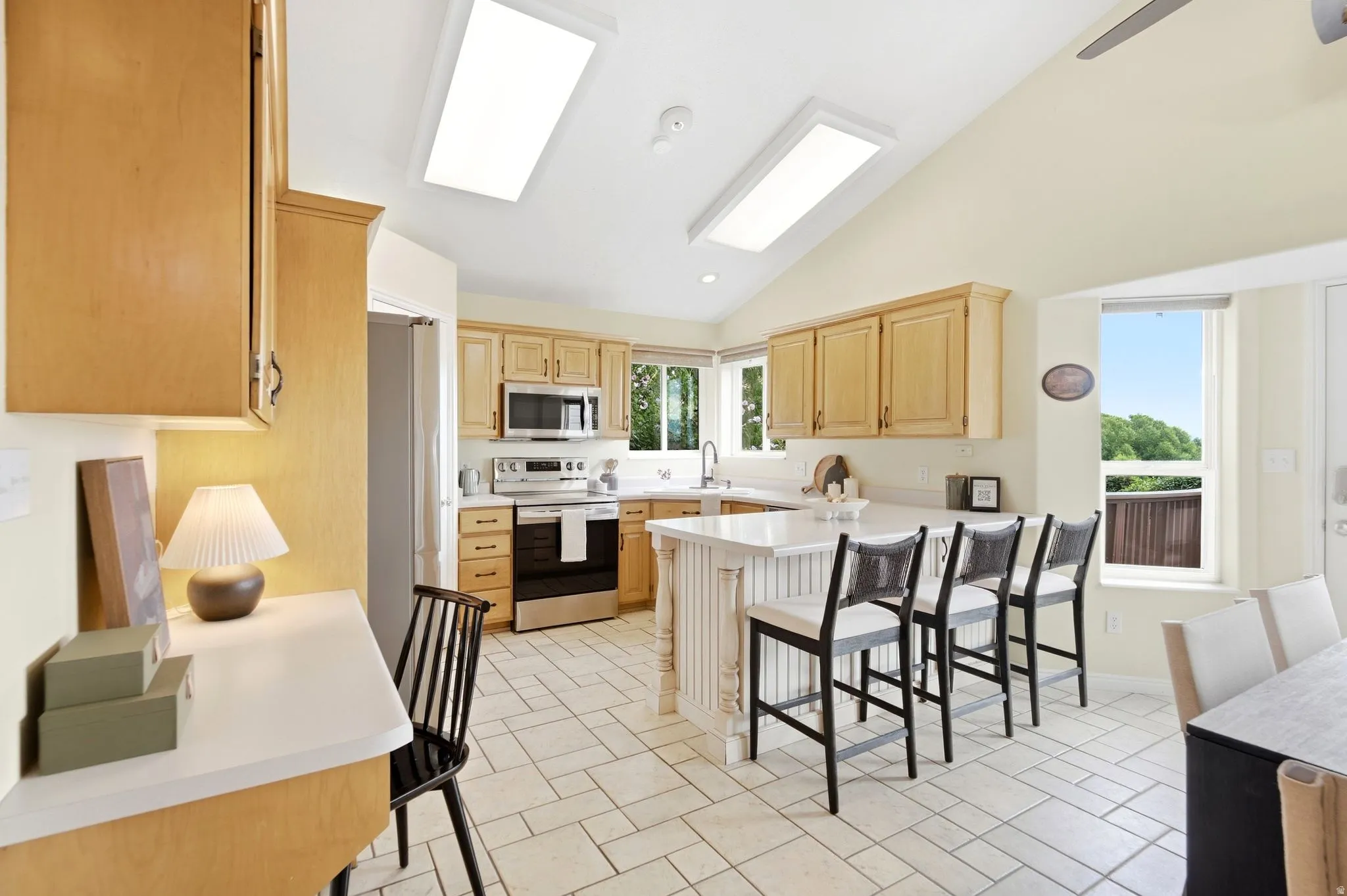 View into the kitchen with the breakfast bar as well as a workstation. View of the pantry, vaulted ceilings, and ample natural light