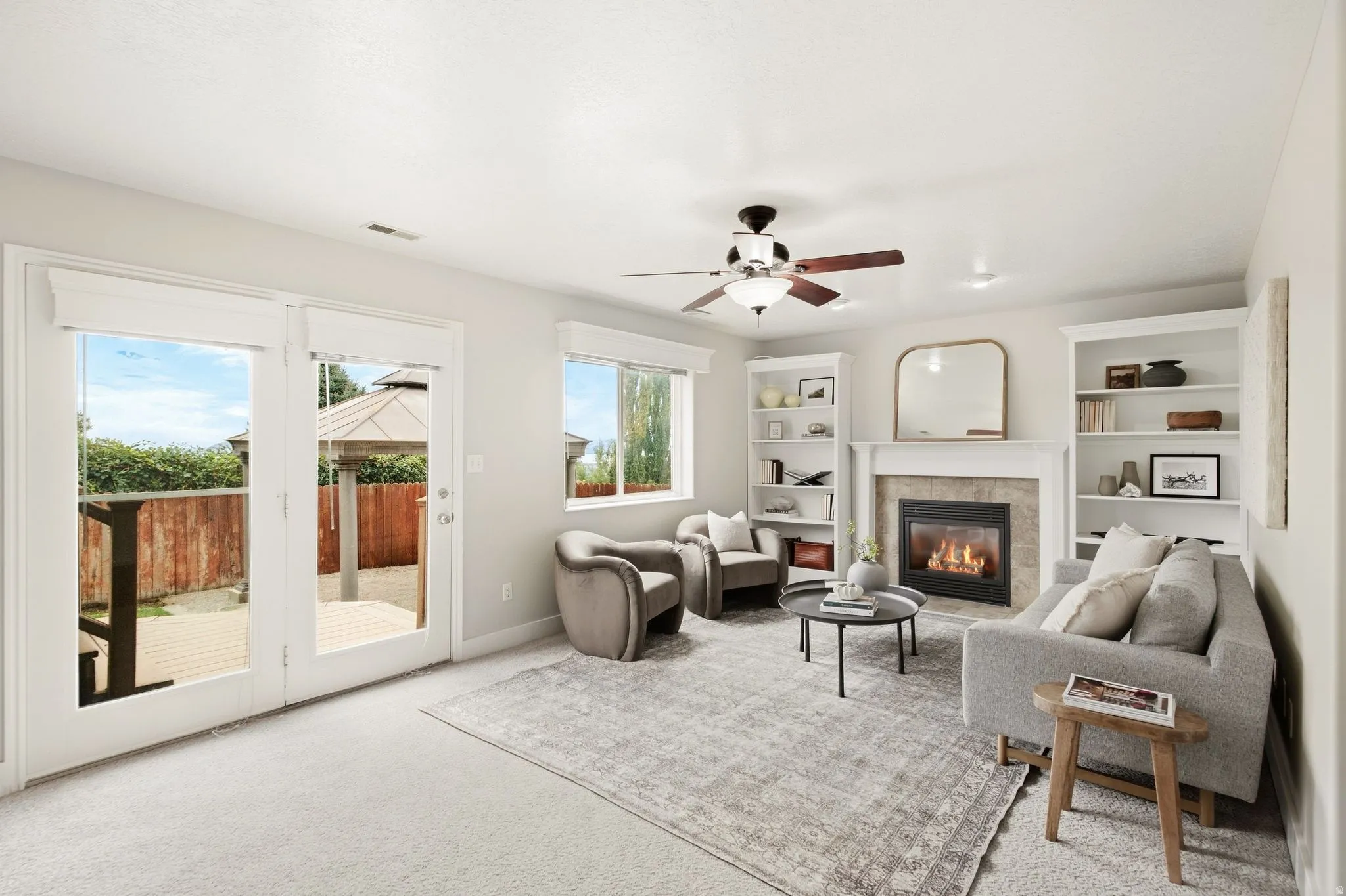 Lower living room off of the garage entrance with a gas fireplace, ample natural light, access to the back deck, and built-in shelving. Pictured glass door to access the back deck