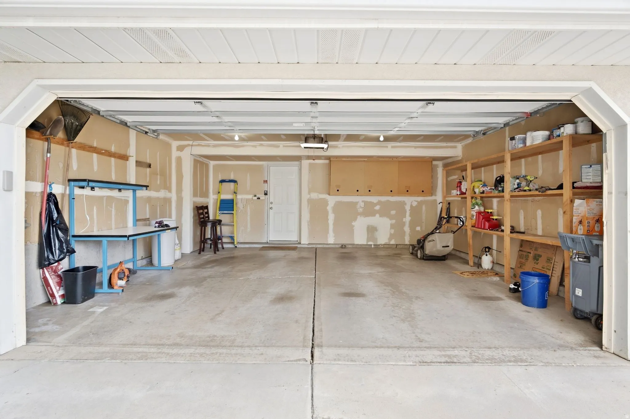 Attached 2-car garage with rear access door into the living room, room for storage, and built-in shelving