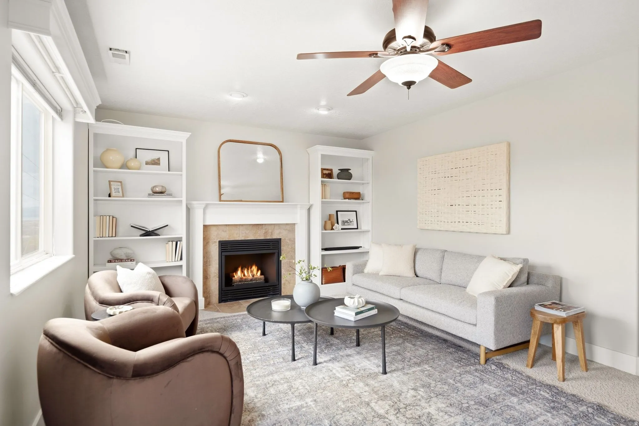 Lower living room off of the garage entrance with a gas fireplace, ample natural light, access to the back deck, and built-in shelving