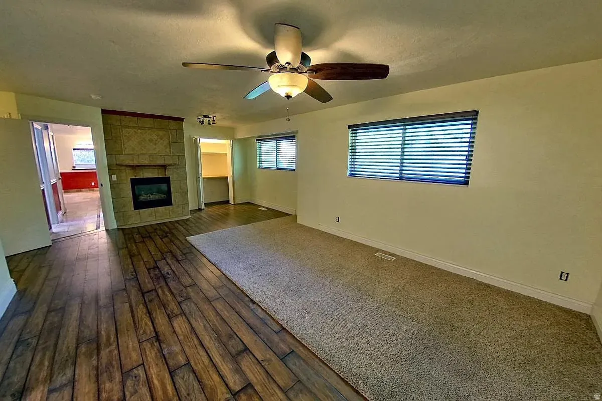 Stone-faced fireplace with a mantel, wood-finish flooring, recessed lighting, and a ceiling fan