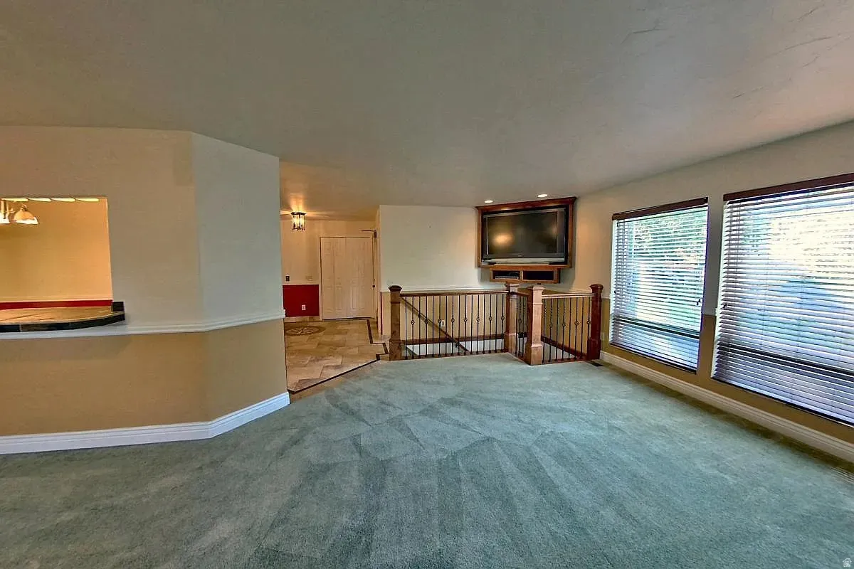Open concept living area featuring expansive windows with blinds, a built-in media cabinet, and a functional half wall with a pass-through opening