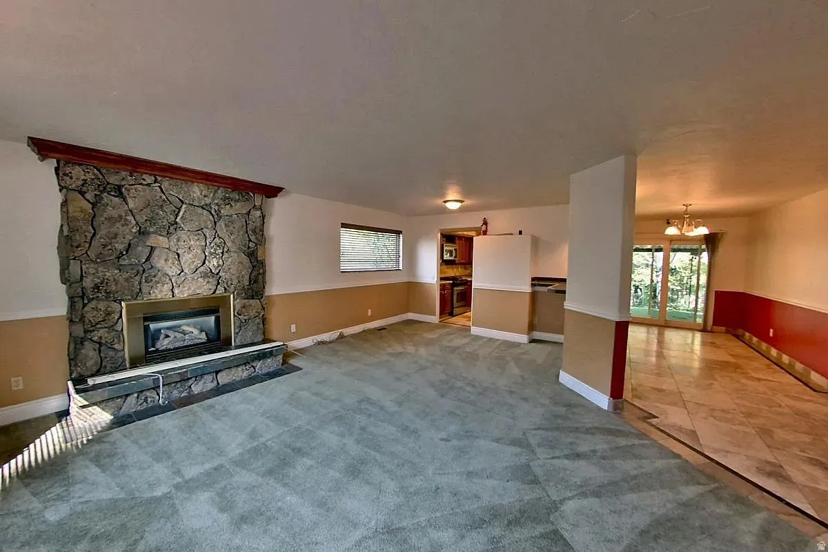 Stone fireplace with hearth, recessed lighting, carpeted area, tiled flooring, and sliding glass doors