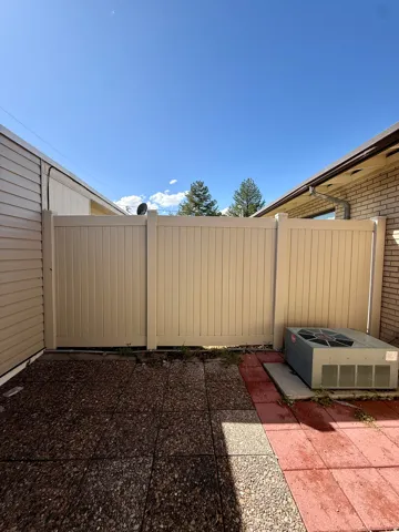 Fenced patio featuring a combination of aggregate and red paver flooring