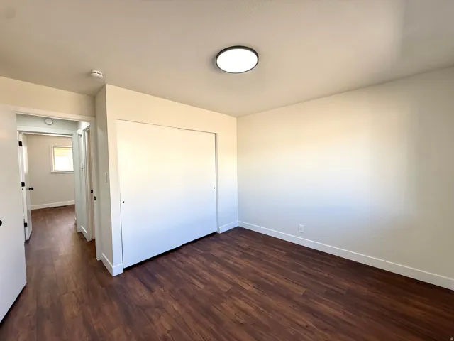 Wood-finish flooring, white walls, and a contemporary flush-mount ceiling light