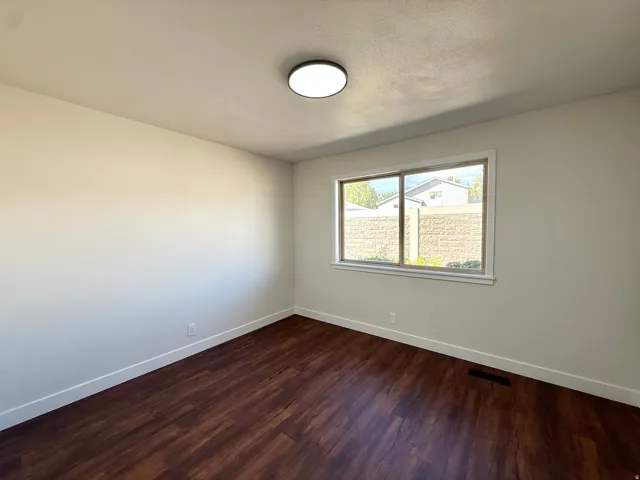 Wood-finish flooring, white walls, and a window with a white frame
