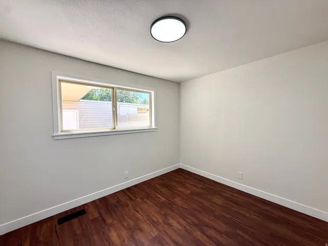 Wood-finish flooring, white walls, and a contemporary flush-mount ceiling light