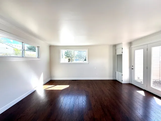 Dark wood-finish flooring, built-in cabinetry, dual French doors, and white trim