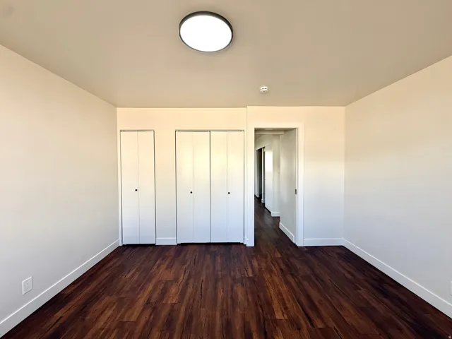 Wood-finish flooring, white walls, and a contemporary flush-mount ceiling light