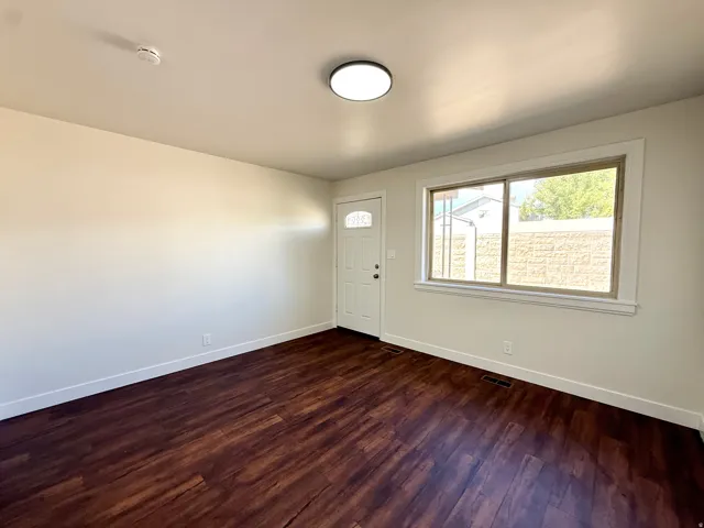 Wood-finish flooring, white trim, recessed lighting, and a front entry door with decorative glass