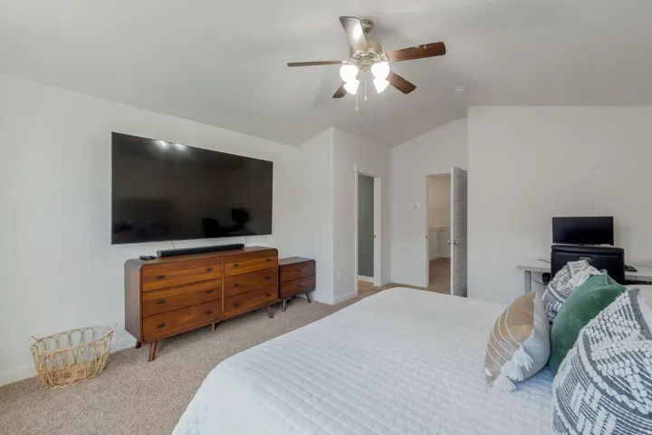 Carpeted room with vaulted ceiling and ceiling fan