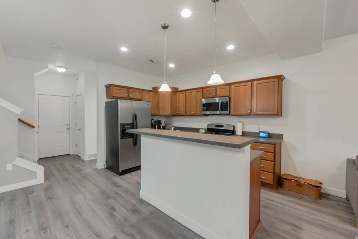 Kitchen featuring wood-finish cabinetry, stainless steel appliances, and two pendant lights