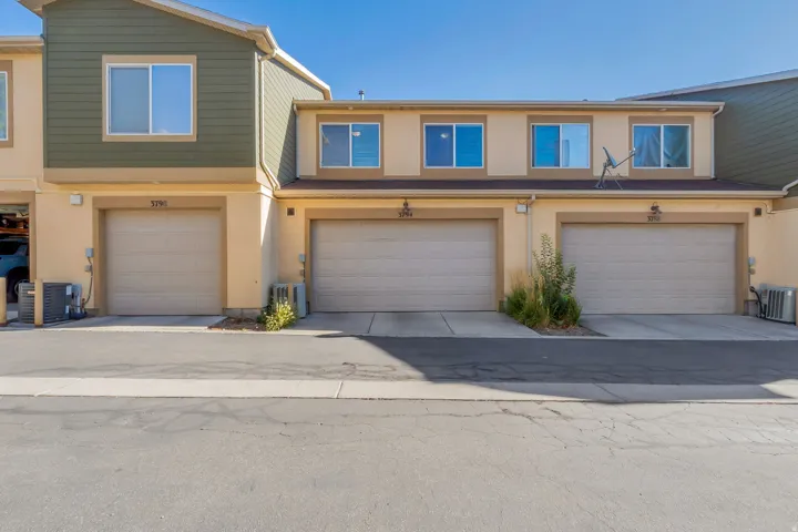 Townhome exterior with light beige stucco and olive green siding accents