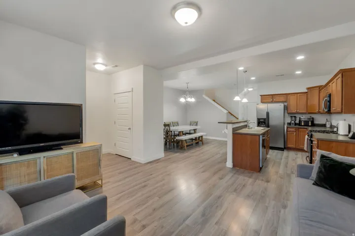 Open-concept living area featuring wood-finish flooring, a kitchen island with sink, and stainless steel appliances