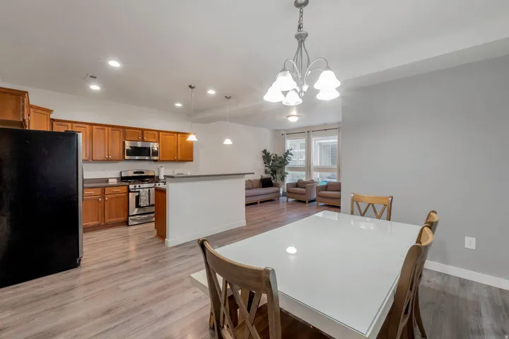 Open-concept living space featuring wood-finish flooring, recessed lighting, a chandelier, and a kitchen with wood cabinetry and stainless steel appliances