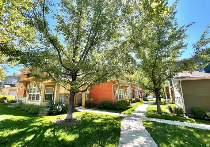 Manicured green spaces with mature trees, a curving concrete pathway, and multiple structures featuring varied siding materials and rooflines