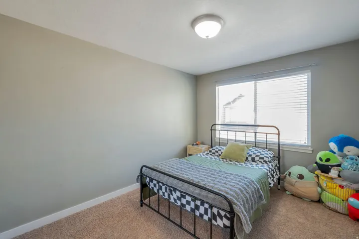 Neutral-toned walls, carpeted flooring, and a large window with blinds
