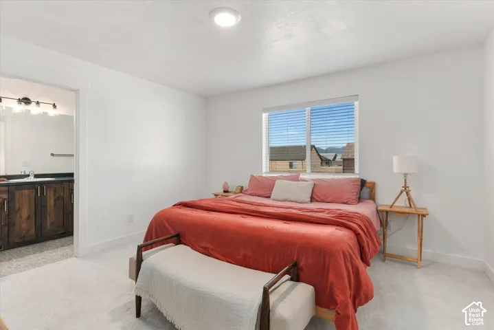 Recessed ceiling lighting, window with horizontal blinds, light-toned carpet flooring, white painted walls, and a doorway to a bathroom