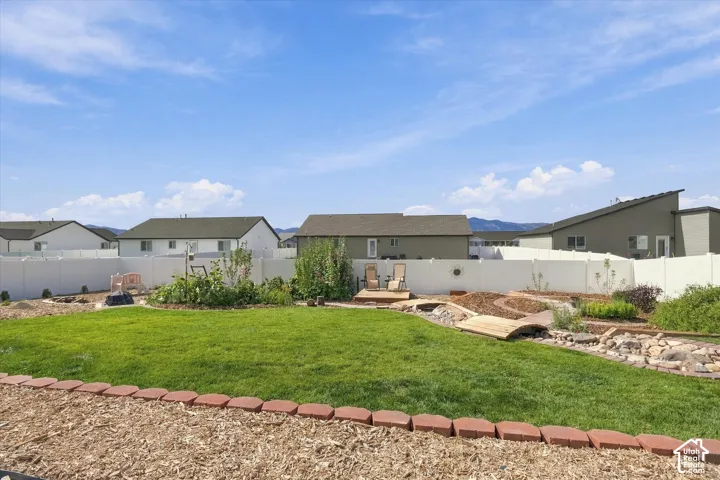 Expansive backyard featuring a manicured lawn, wood chip landscaping, and a decorative rock riverbed