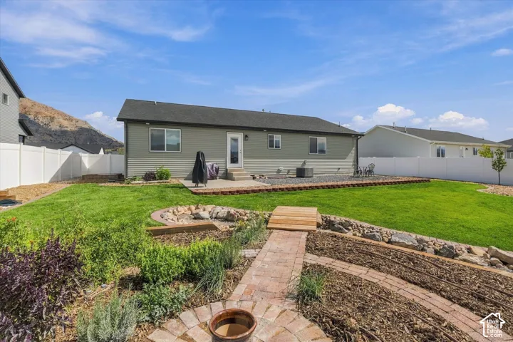 Expansive backyard featuring a manicured lawn, a paved patio, and a brick pathway