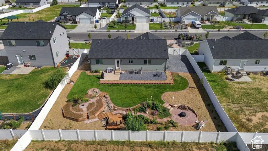 Expansive backyard featuring a manicured lawn, multi-level terraced landscaping, a built-in fire pit, and a decorative water feature