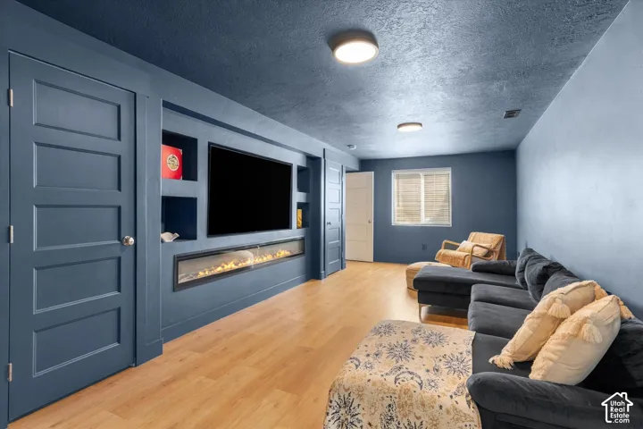 Recessed media wall with built-in shelving, linear electric fireplace, and wood-finish flooring