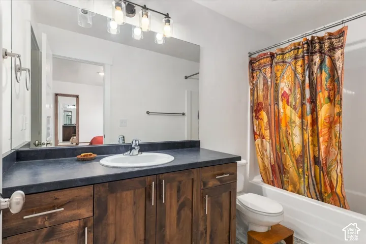 Wood-finish vanity with a dark countertop and integrated sink, complemented by a large wall-mounted mirror