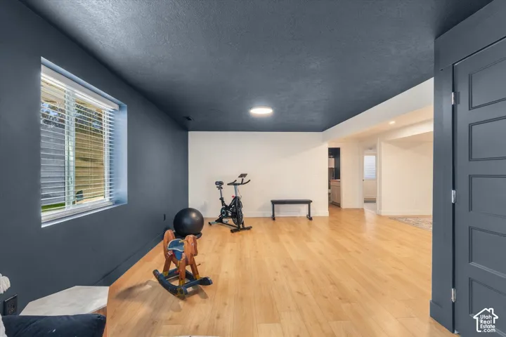 Spacious room featuring wood-finish flooring, a window with blinds, and recessed lighting