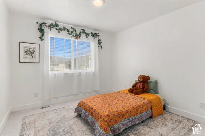 Recessed ceiling lighting illuminates the room with bright white walls and a window with white blinds and sheer curtains