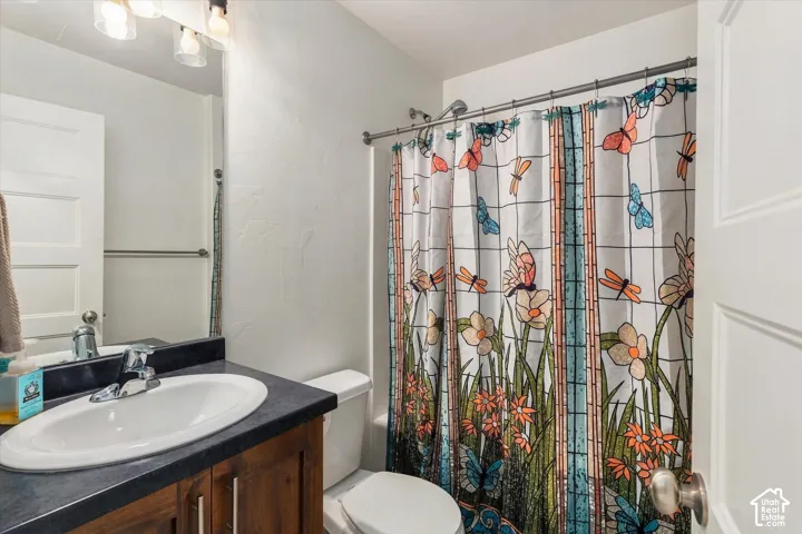 Bathroom featuring a single vanity with a dark countertop, an undermount sink, and wood-finish cabinetry