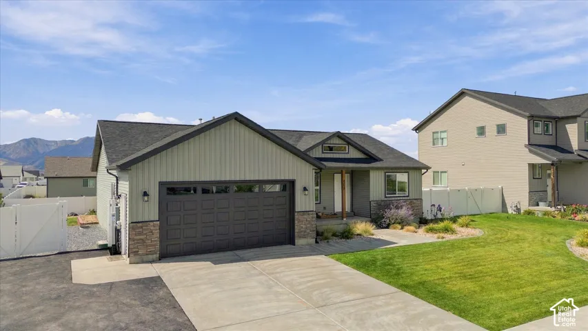 Single-story residence featuring light green vertical siding, stone accents, and a dark asphalt shingle roof