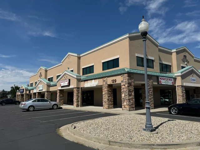Multi-tenant commercial building featuring a stucco facade, stone column accents, and distinct storefront entrances