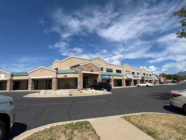 Two-story commercial building featuring multiple storefronts, stone veneer accents, and a distinctive roofline