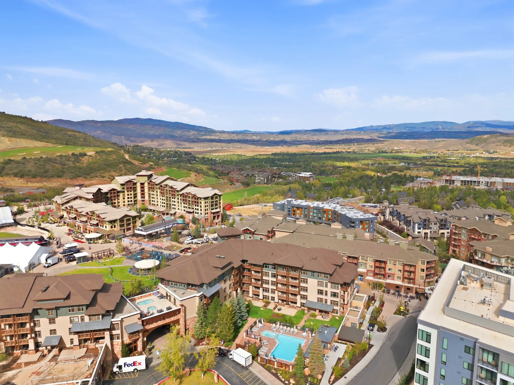 Expansive multi-building complex featuring multiple swimming pools, structured landscaping, and a mountainous backdrop